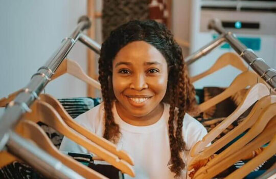 Afrikstabel-CEO-Founder-standing-between-fabrics-in-collaboration-with-DexStitches-Fashion-website